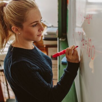 Eine Schülerin am Whiteboard rechnet ein Formelgleichung.