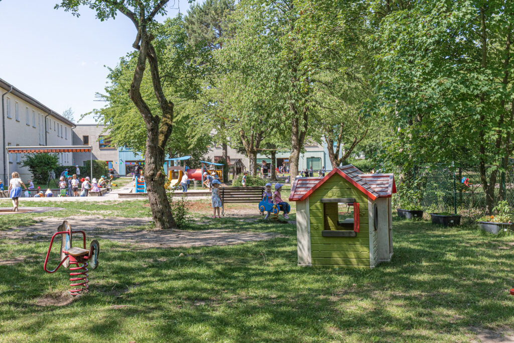 An einem sonnigen Tag spielen Kinder im grünen Garten der Kita Kaulsdorf.