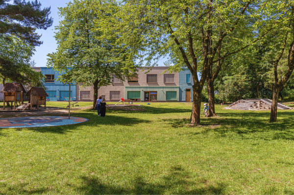 Weitläufiges Außengelände der BEST-Sabel Kita Kaulsdorf mit grünem Rasen und Bäumen