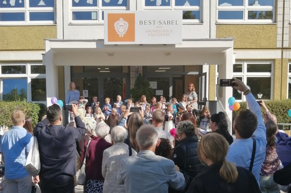 Eltern und Gäste schauen auf den Haupteingang der BEST-Sabel Grundschule Kaulsdorf, wo die neue Klasse 1a sich zum Gruppenfoto aufgestellt hat