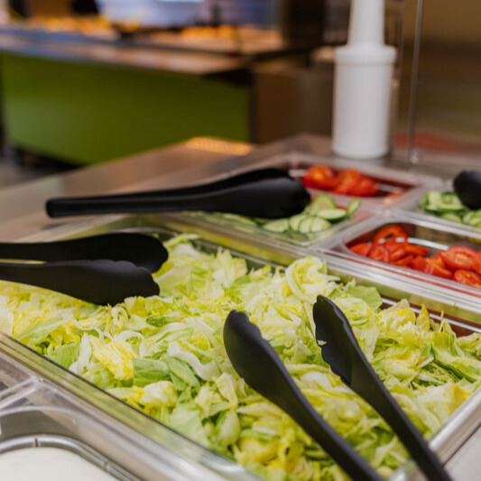 Bunte, frische Salatbar mit grünen Gurken, roten Tomaten zur Selbstbedienung