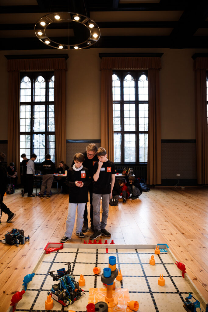 Robotik-Team mit ihrem Trainer vor dem VEX IQ Spielfeld